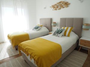 um quarto com 2 camas e cobertores amarelos em Charming V2 next to ocean, golf & natural reserve em Albufeira