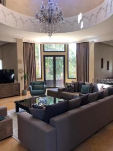 een grote woonkamer met een bank en een kroonluchter bij Exceptionnel Villa 6 Rooms 12 guests Big Pool in Marrakesh