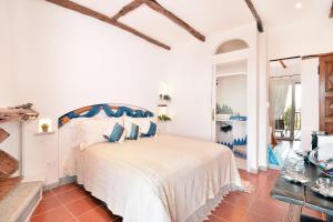 a white bedroom with a bed with blue pillows at Karamare in Stintino