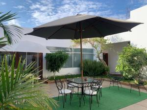 a table and chairs with an umbrella in a courtyard at Renace Suites in Tacna