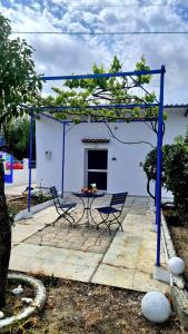 un patio con 2 sillas y una mesa frente a un edificio en Blue and White, en Kremasti