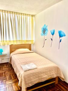 1 dormitorio con 1 cama con flores azules en la pared en Pershing, depa bonito, 3camas wifi/cable, en Lima