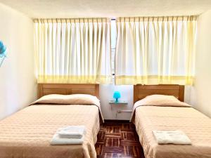 1 dormitorio con 2 camas y una ventana con cortinas en Pershing, depa bonito, 3camas wifi/cable, en Lima