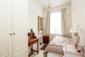 a bedroom with a bed and a desk and a window at Large 3 bed flat in central Wimbledon in London