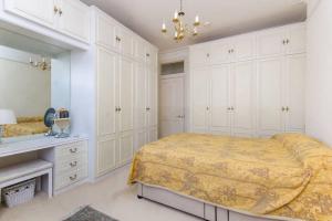 a white bedroom with a bed and a mirror at Large 3 bed flat in central Wimbledon in London
