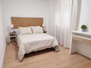 een slaapkamer met een wit bed en een houten vloer bij ÓPERA CAMPOAMOR (CENTRO CIUDAD, PLAZA DE GARAJE) in Oviedo