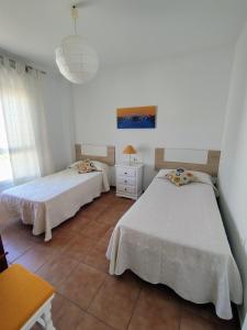 コニル・デ・ラ・フロンテーラにあるVerdeMar-Terraza-Sólo familiasのベッドルーム1室(ベッド2台、テーブル、ランプ付)