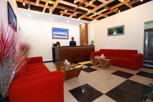 Eine Lobby mit roten Sofas und einem Mann im Hintergrund in der Unterkunft Grand Castle Hotel & Resturant in Comilla