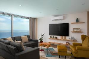 a living room with a couch and a flat screen tv at Peak A Boo Private Heated Pool and Private Parking in Câmara de Lobos
