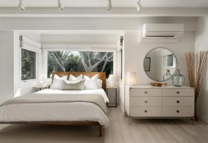 a white bedroom with a large bed and a mirror at Palm Cottage in Montecito