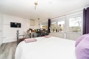 1 dormitorio con 1 cama blanca y cocina en 11 Boutique studio apartment perfect for peaceful getaway, secluded garden, quiet location, en High Wycombe