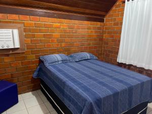 格雷夫森德的住宿－Lindo chalé em Gravatá - Condomínio Mont Blanc V，一间设有蓝色床的砖墙卧室