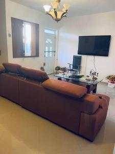 un sofá marrón en la sala de estar con TV en Villa Esperança, en Tarrafal