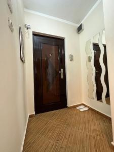 a hallway with a black door and a wooden floor at SHoliday Studio Apartament modern cu parcare gratuită în Timișoara in Timişoara