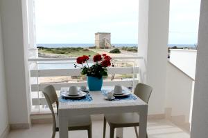 a table with a vase of flowers on a balcony at Altomare Case Vacanza in Torre Lapillo