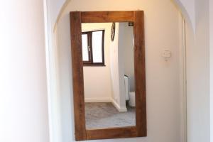 a mirror with a wooden frame hanging on a wall at Garland Modern Apartment with Private Garden & Parking Dartford 5 in Kent