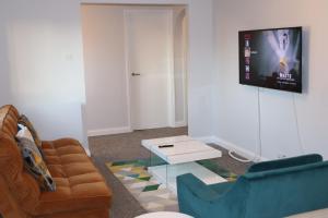 ein Wohnzimmer mit einem Sofa, einem Tisch und einem TV in der Unterkunft Garland Modern Apartment with Private Garden & Parking Dartford 5 in Kent