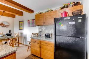 a kitchen with a black refrigerator and wooden cabinets at Rustic 3 Br Condominium Condo in Crested Butte