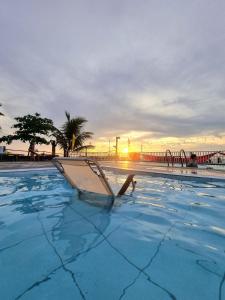 a swimming pool with a chair in the water with the sunset at Medano Sunset Resort in Mambajao
