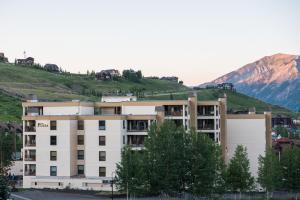 a white building with a mountain in the background at Large 2 Br With Open Floorplan Condo in Crested Butte