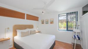a white bedroom with a bed and a window at Coast Yamba - Adults Only in Yamba