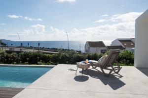 a chair sitting next to a swimming pool with the ocean at Green&Houses in Ponta Delgada