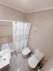 a white bathroom with a toilet and a sink at Alquiler departamento San Lorenzo in Tandil
