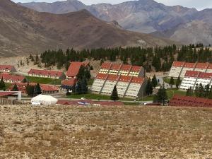 a group of buildings in a field with mountains in the background at Departamento dentro del centro de sky Valle de Las Leñas, Edificio Esparta in Las Lenas