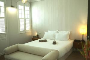 ein Schlafzimmer mit einem weißen Bett und einem Sofa in der Unterkunft Maison Victoire, Pointe-à-Pitre in Pointe-à-Pitre