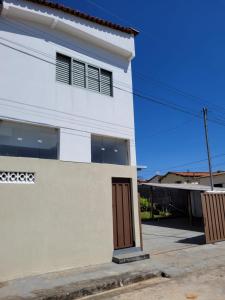 a white house with a brown door on a street at Serra da Canastra - Casa em Vargem Bonita/MG in Vargem Bonita