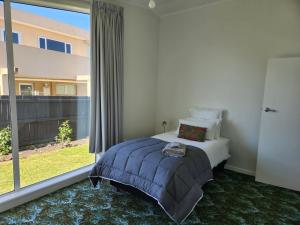 a bedroom with a bed and a large window at Beautifully renovated townhouse, easy walk to CBD in Blenheim