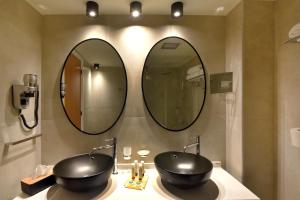 a bathroom with two sinks and two mirrors at Hotel Hermes in Ermoupoli