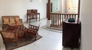 a living room with chairs and a table and a balcony at Maison Petite Singapore in Pondicherry
