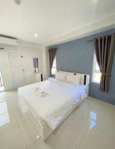 a large white bed in a room with windows at SC Residences in Suratthani