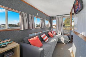 uma sala de estar com um sofá cinzento e janelas em Caloundra Houseboats em Pelican Waters