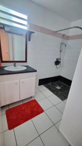 a bathroom with a sink and a shower with a red rug at Domaine de Portland in Le Moule