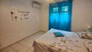 a bedroom with a bed with a blue curtain at Domaine de Portland in Le Moule