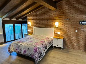 a bedroom with a bed and a brick wall at Apartamentos A Fala en Trevejo y San Martin de Trevejo, Sierra de Gata in Trevejo