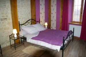 a bedroom with a bed with purple sheets and two lamps at Gite au Chalet in Laferté-sur-Aube