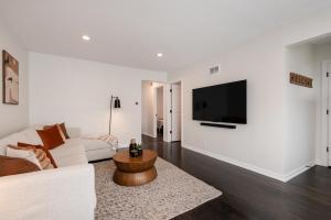 ein Wohnzimmer mit einer weißen Couch und einem TV an der Wand in der Unterkunft Luxurious House, 25 min Downtown, 10min Midway in Burbank