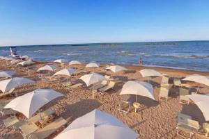 a bunch of white umbrellas on a beach at Apartment Largo del Teatro in Porto San Giorgio