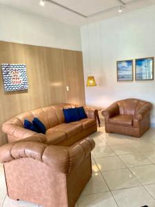 a living room with two leather couches and two chairs at Apartamento Frente para o mar in Ilha Comprida