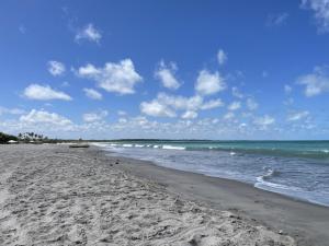 una playa de arena con el océano y nubes en el cielo en Casa Temporada Lucena -PB, en Lucena