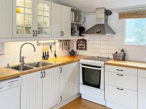 Holiday home NYNÄSHAMN في نينس هامن: مطبخ مع دواليب بيضاء ومغسلة