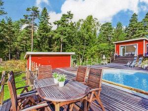 una mesa de madera y sillas en una terraza junto a la piscina en Holiday home NYNÄSHAMN, en Nynäshamn