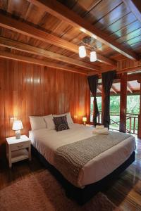 1 dormitorio con 1 cama grande y paredes de madera en The Wooden House Mindo, en Mindo