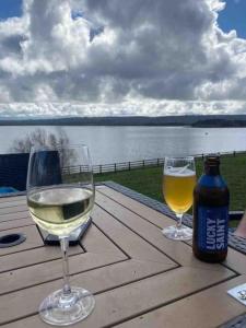 two glasses of white wine and a bottle on a wooden table at 17A Stella house nr Bath in Radstock +18 photos