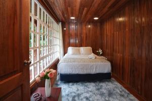 a bedroom with a bed in a room with wooden walls at The Wooden House Mindo in Mindo
