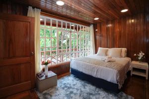 a bedroom with a bed and a large window at The Wooden House Mindo in Mindo