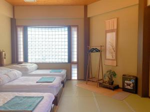 Zimmer mit 4 Betten und Fenster in der Unterkunft 雅 in Nishinotōindōri